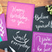White brush pen lettering and highlights on pink, purple, and black paper cards