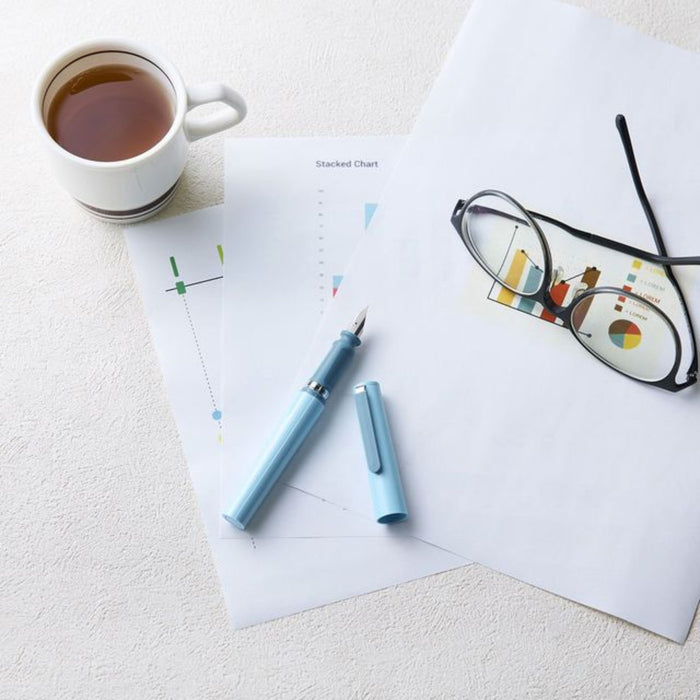 Green fountain pen on papers with glasses and tea cup for writing and planning