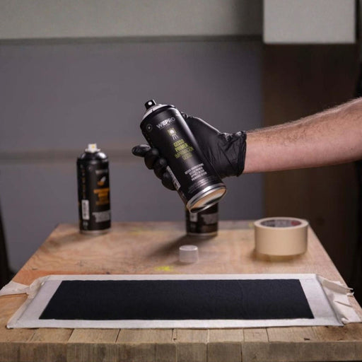 Artist holding MTN WEPRO Gesso Primer spray can over prepared art surface
