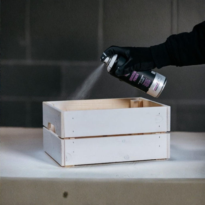 Spraying MTN WEPRO Universal Primer onto a wooden crate for improved paint adhesion
