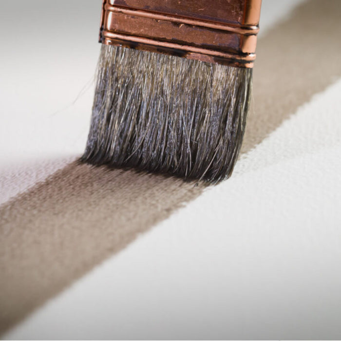 Watercolour brush applying a wash across textured Arches rough watercolour paper surface