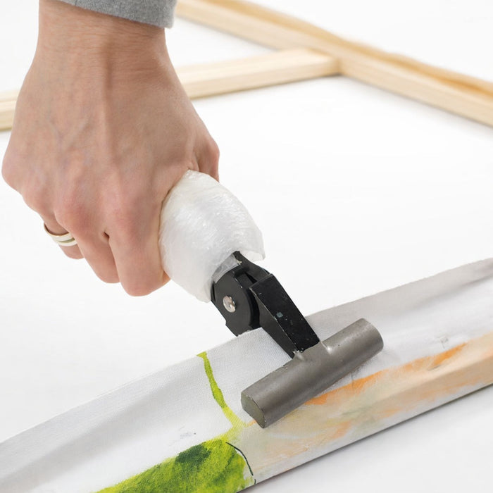 Artist pulling canvas tight with stretching pliers during framing