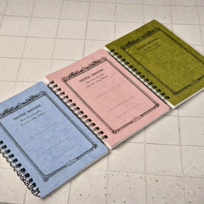 Apica CD Twin Ring Notebooks in Wisteria, Peach, and Olive arranged on tabletop